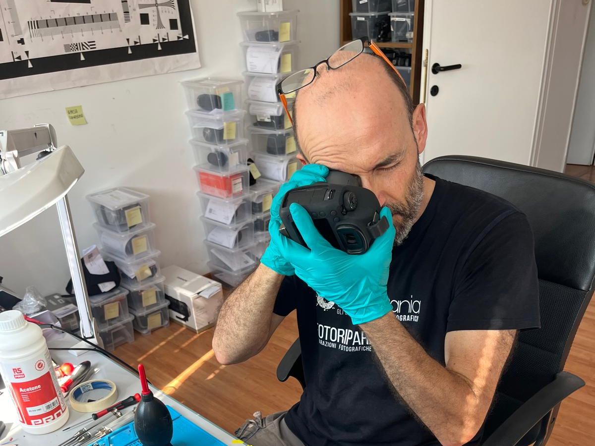 Tecnico che ispeziona un corpo macchina attraverso il mirino durante un check-up completo nel laboratorio di Ancona
