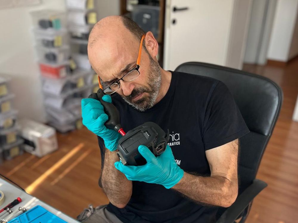 Francesco Borioni pulisce un corpo macchina con la pompetta al banco del laboratorio Fotoriparatore di Ancona